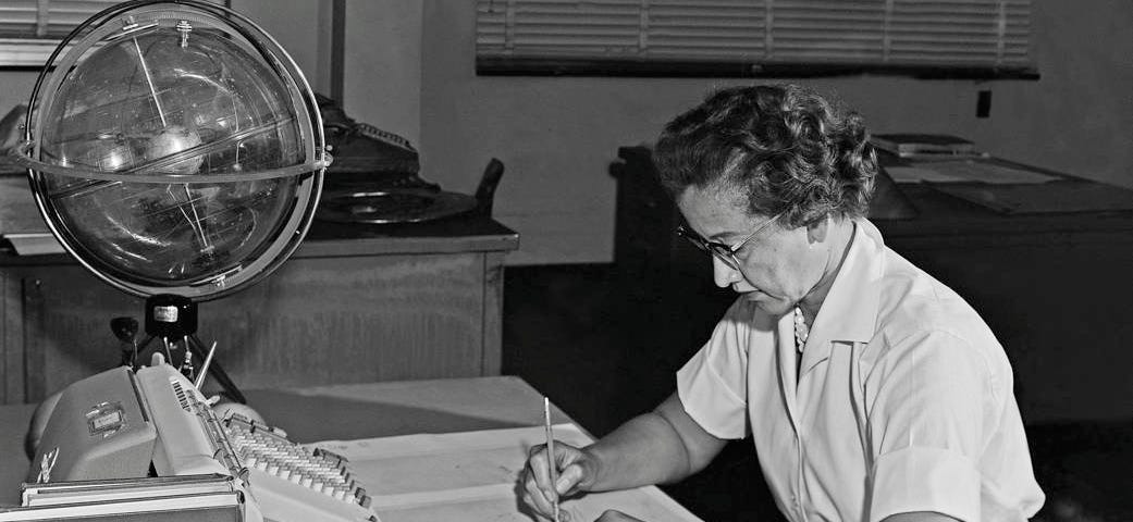 Katherine Johnson at work at NASA. She is sitting at a desk writing.