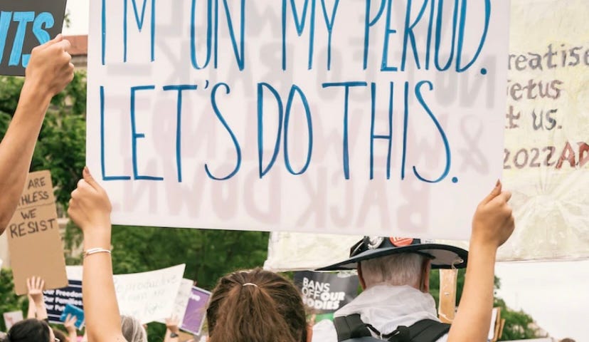 Woman holding sign that says I’m on my period. Let’s do this.