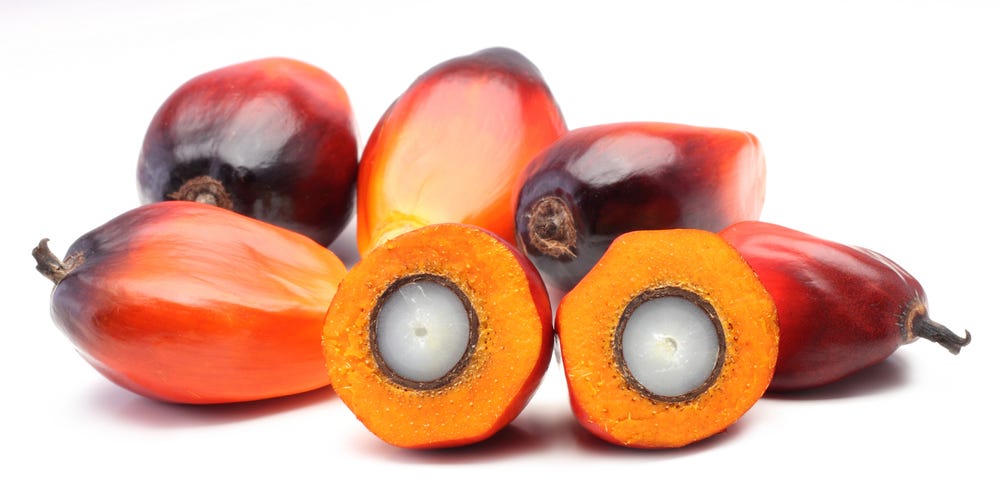 Picture of several palm oil fruit, one of which is cut open to reveal the inside.
