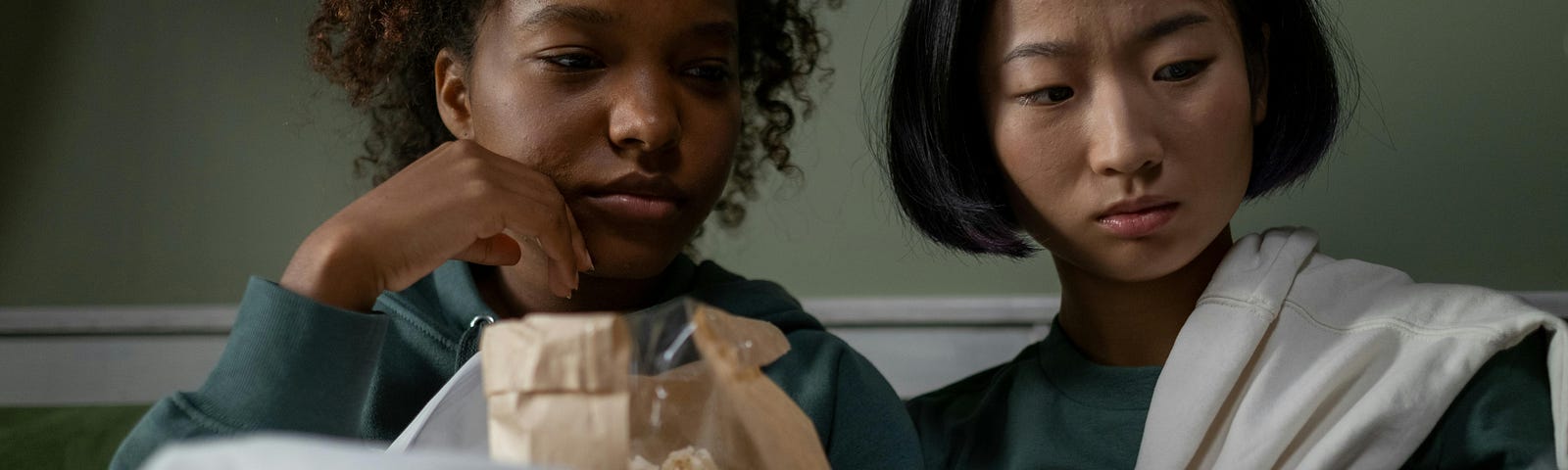 two women watching a TV, with sad expression