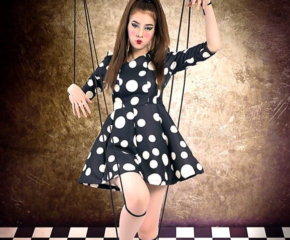 Young woman made up like a puppet doll with puppet strings attached to her