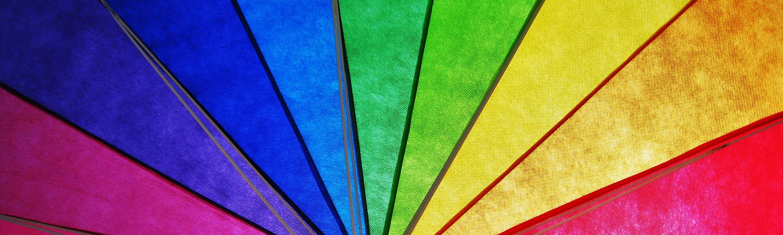 Inside of rainbow umbrella with sun shining through it