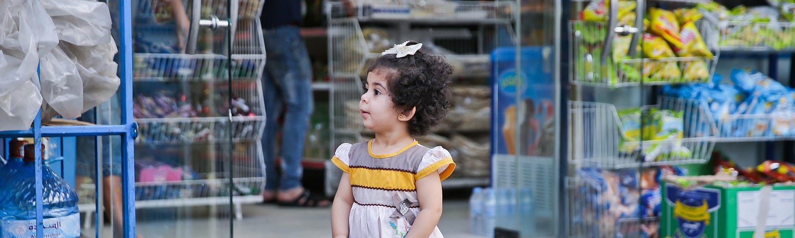 Little girl holding coin purse in front of store.