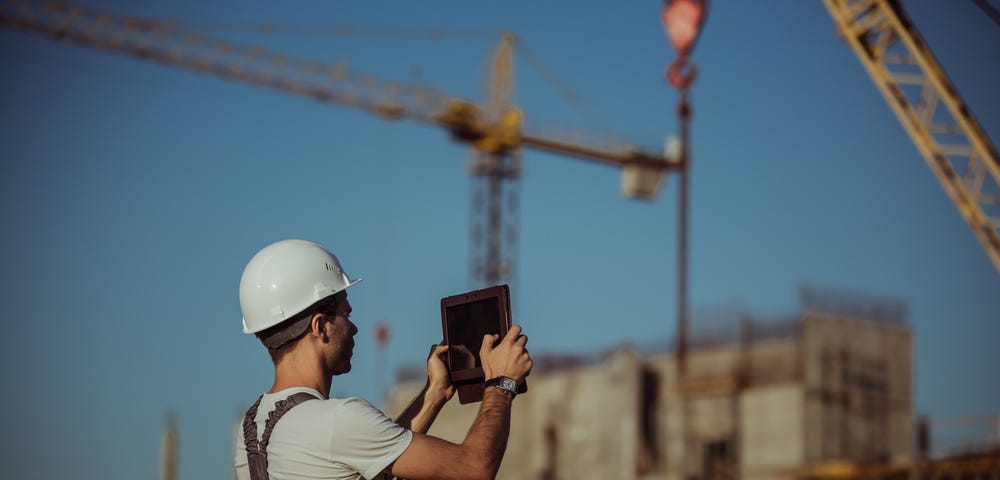 Worker taking a picture with an iPad on a construction site