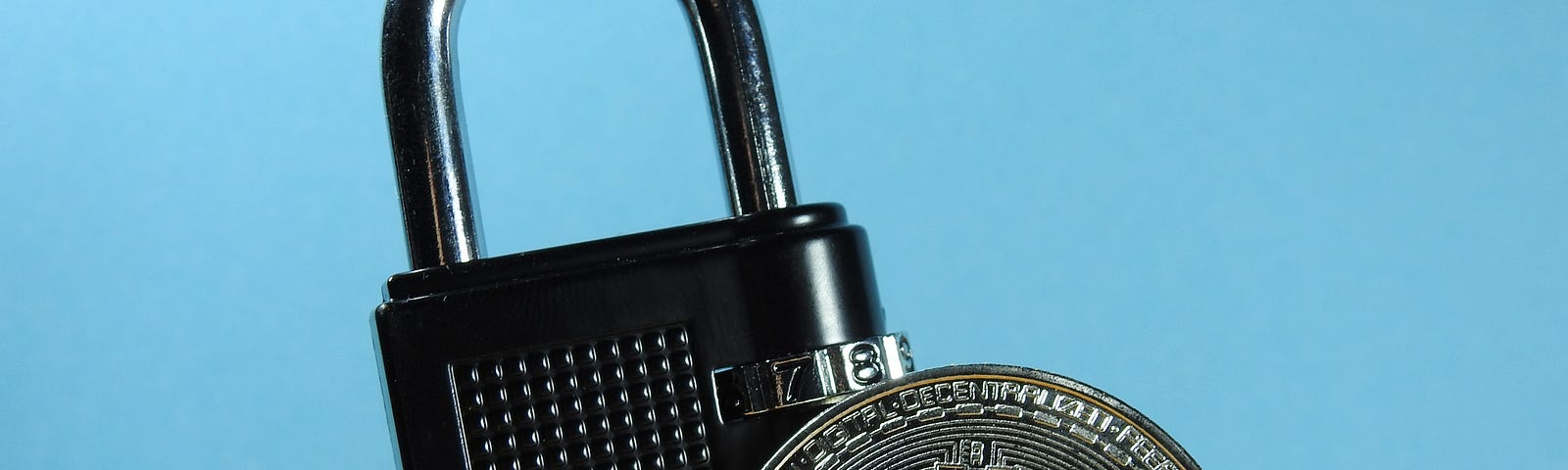 A bitcoin cryptocurrency coin in sand with a black locked padlock
