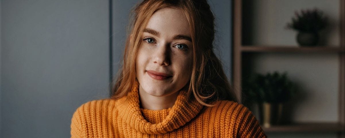 Red haired woman wearing a large orange jumper.