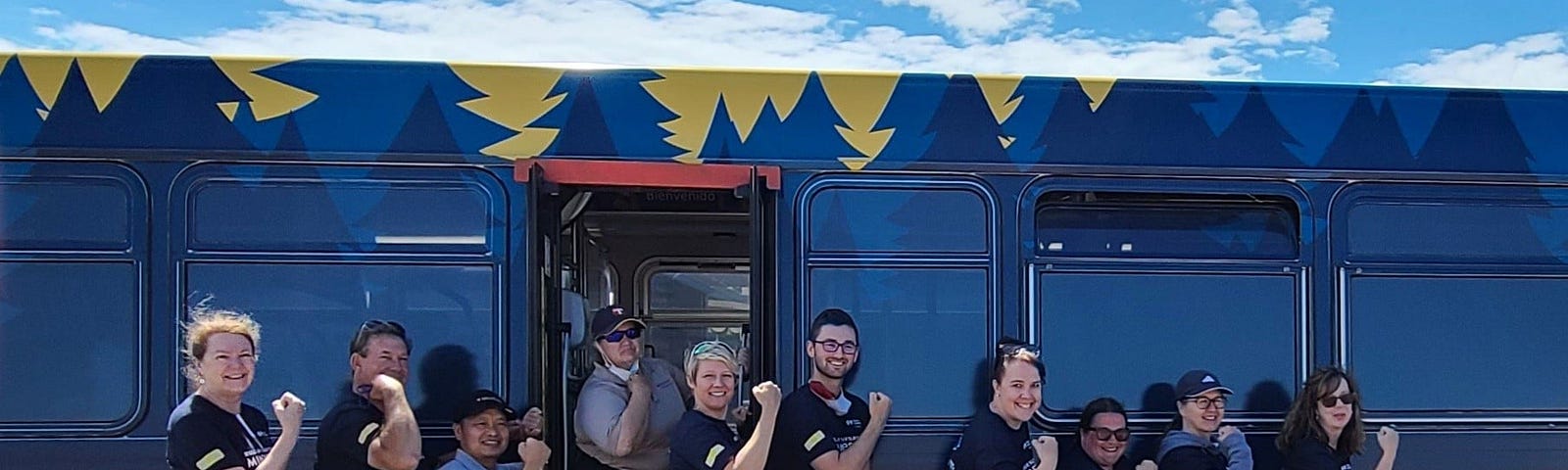 Transit workers flex their arm muscles, posing in front of a bus repurposed as a mobile vaccine clinic