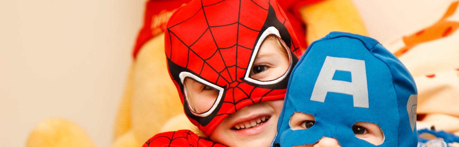 Two kids wearing halloween costumes. Left is spider man, while the right is captain America