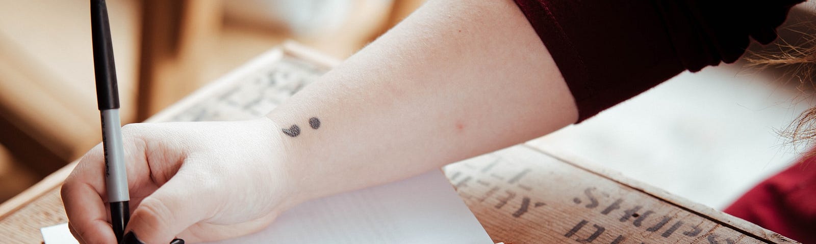 Woman writing on blank journal page with a black pen