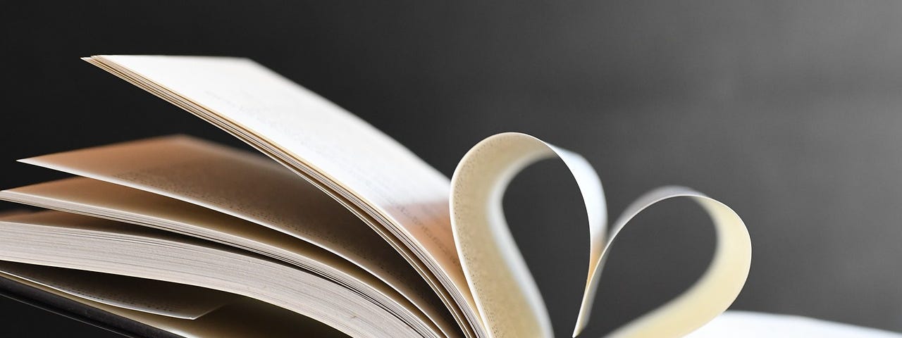 A photo of an opened book in which two pages are folded together and resemble a human heart