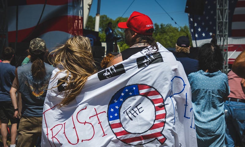 A group of Trump supporters wearing a pro-QAnon banner