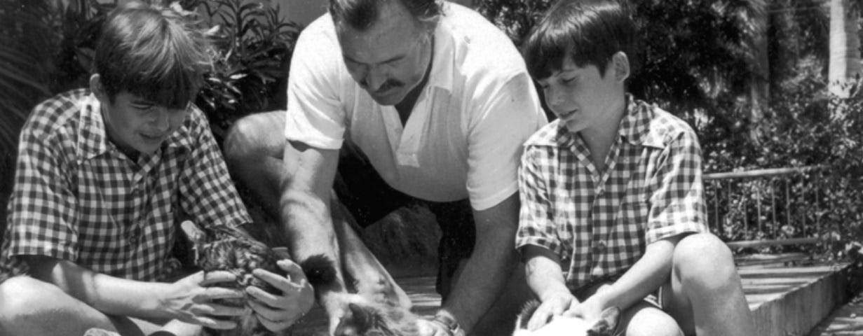 Famous author Ernest “Papa” Hemingway with his two son Patrick on the left and Gregory on the right with their cats in Cuba.