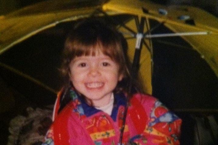 A young Hannah Fulmer holds a yellow umbrella.