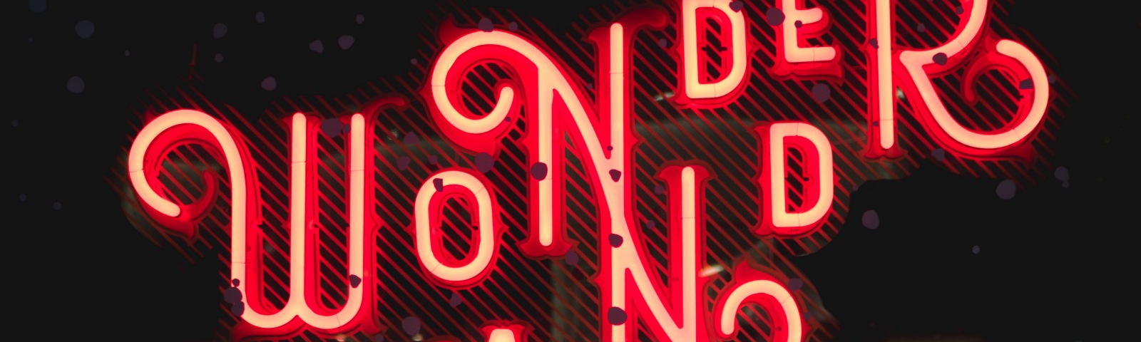 Red neon on Wonder Land in curly art deco text. With a large M in front added by Zane Dickens