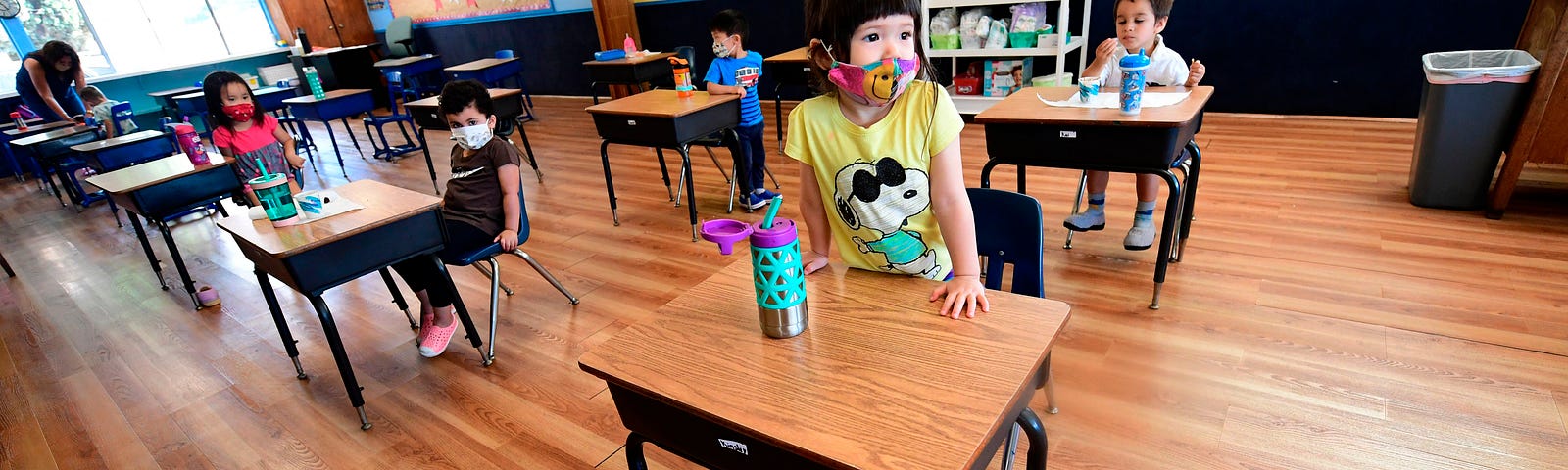 Children in a pre-school class wear masks and sit at desks spaced apart as per coronavirus guidelines during summer school.