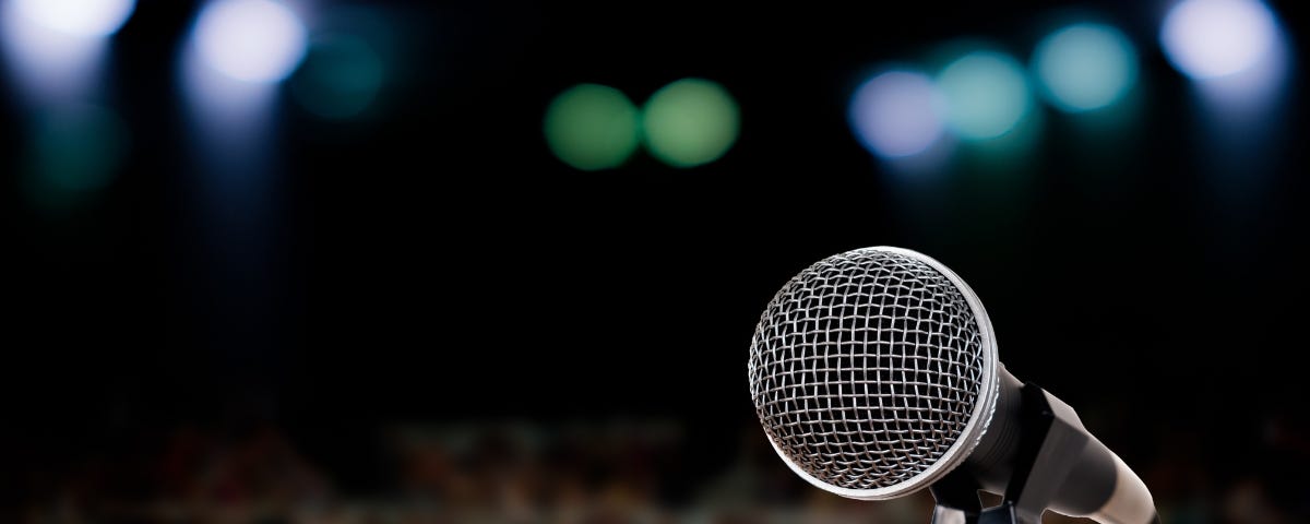 a microphone with an audience and large room behind it