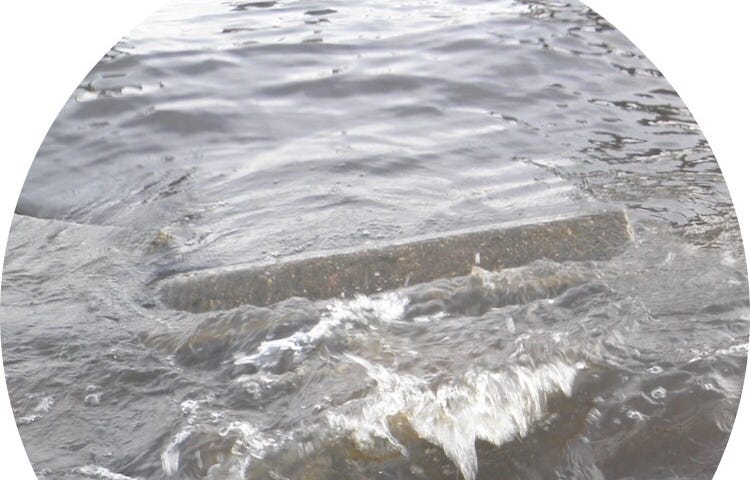 Lake wave crashing over abandoned cement steps of a seawall.