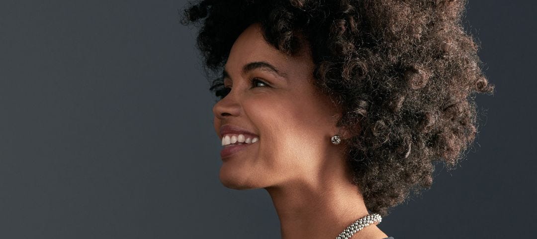 smiling professional woman in a black dress and silver necklace