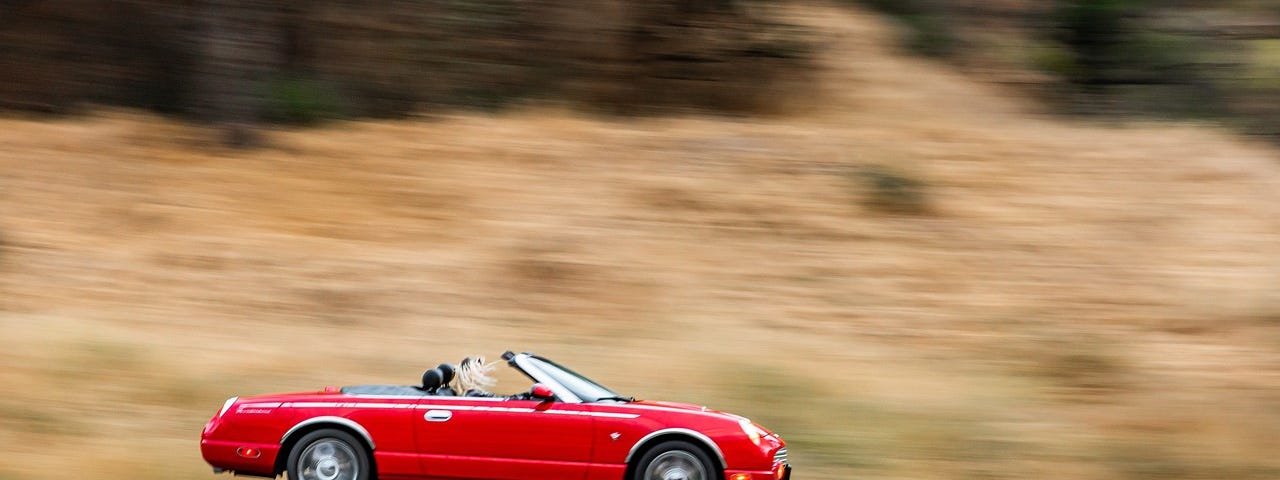 Red sexy car zooming on the road.