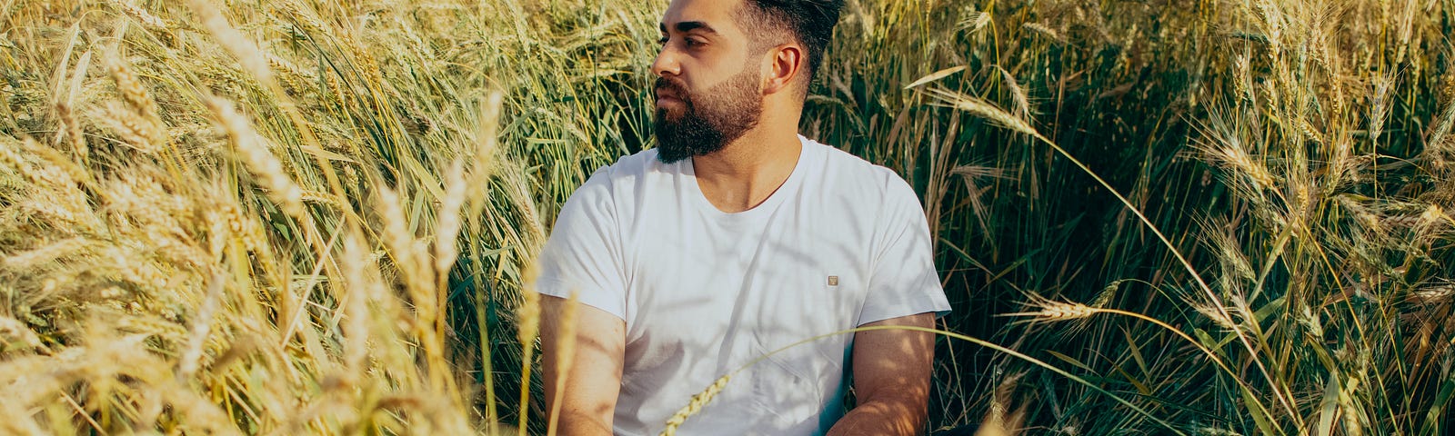 A man sitting in a field staring out into the distance