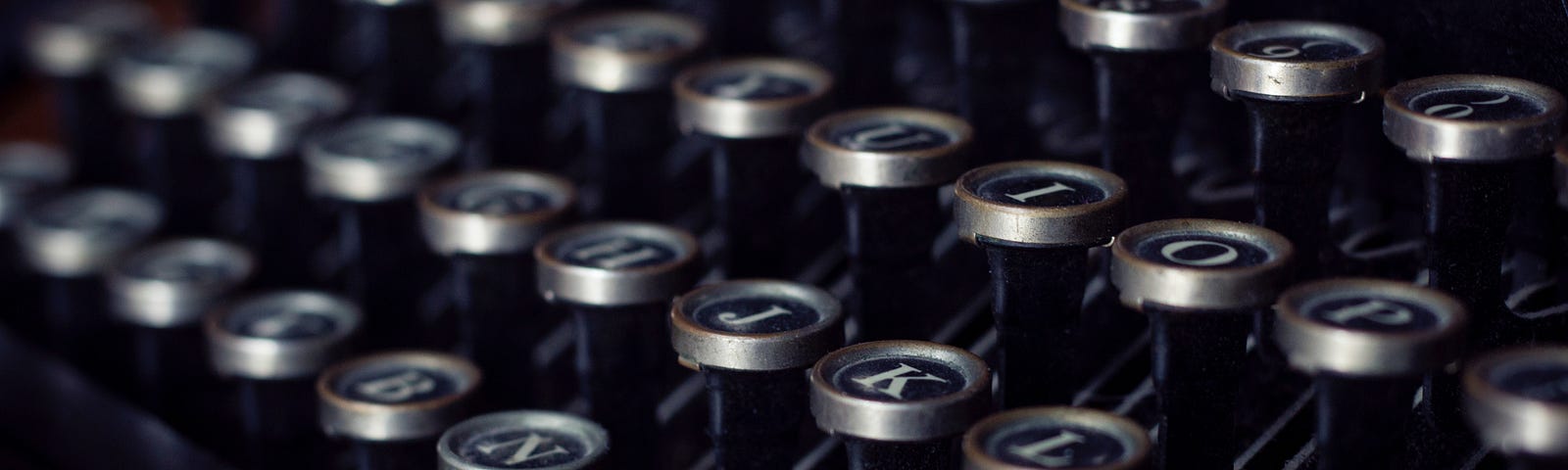 A close up of a vintage typewriter keyboard with circular keys and white letters on black round tiles for each key.