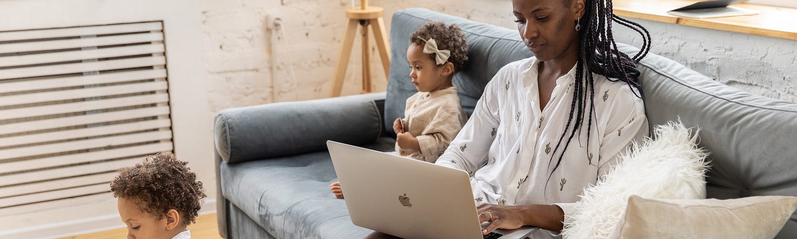 Woman in White long sleeve shirt sitting on grey couch using a computer with 2 kids | Awesome Websites For Content Writers: Work From Home | Money, Freelance, Work from home, make money from home, Medium