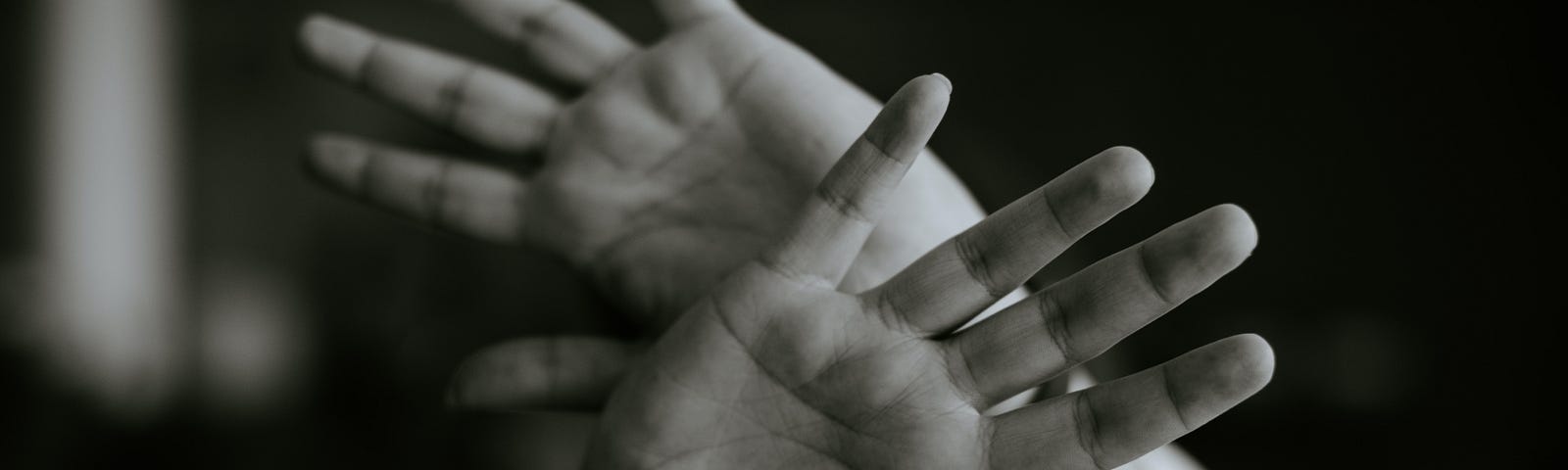 a child’s hand crossed at the wrist, in front of their face. black and white.