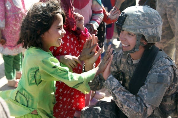 An Afghan girl greets an American female soldier.