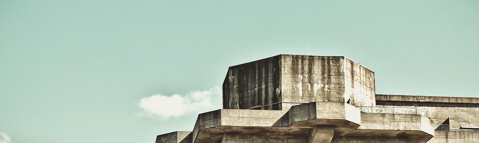 An old, desolate concrete fortress stands against a clear blue sky.