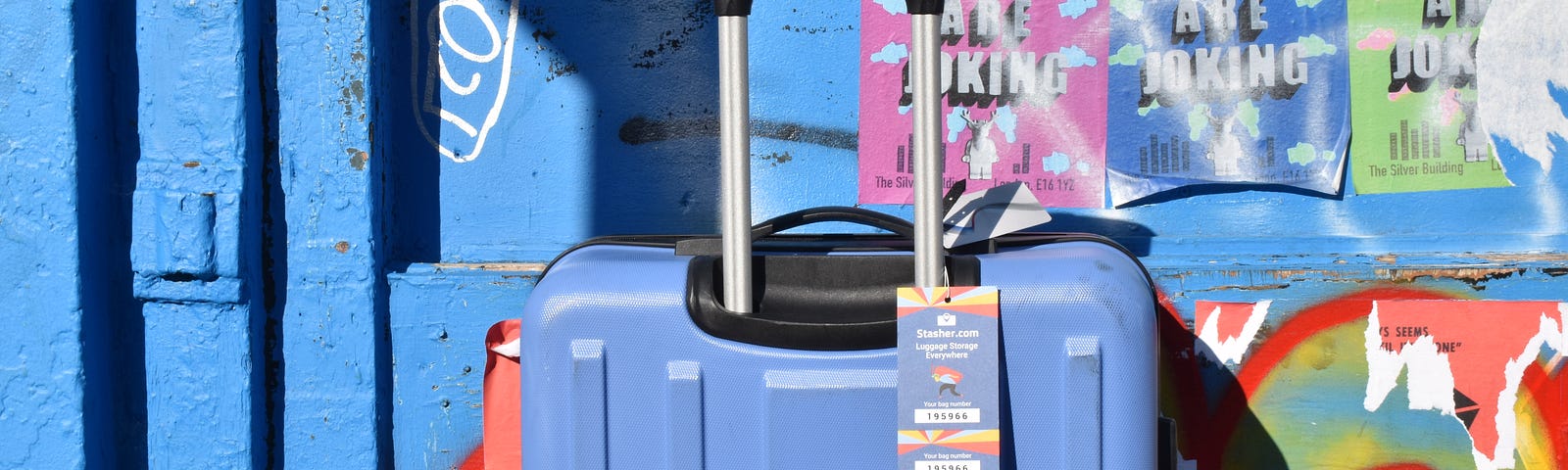 Blue Stasher suitcase set against a graffiti covered wall