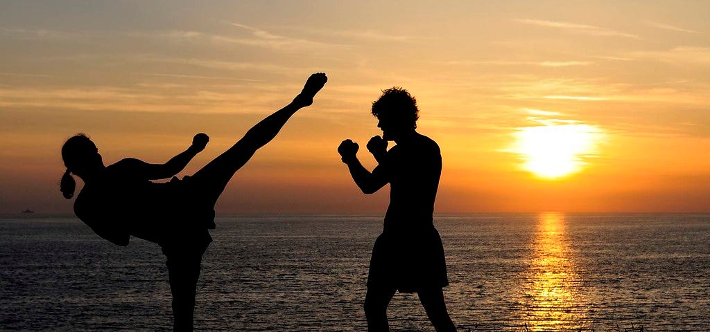 A photo of two people kickboxing at sunset.