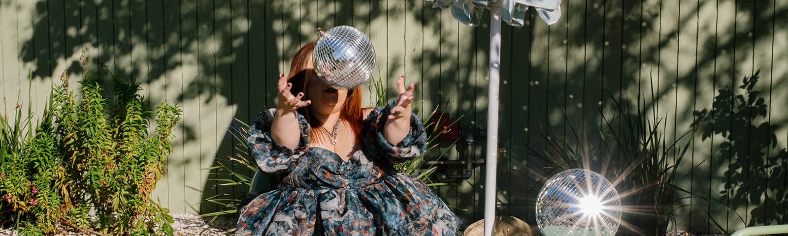 A photo of Ashley Couto throwing up a disco ball so it looks like she’s making it hover above her hands.