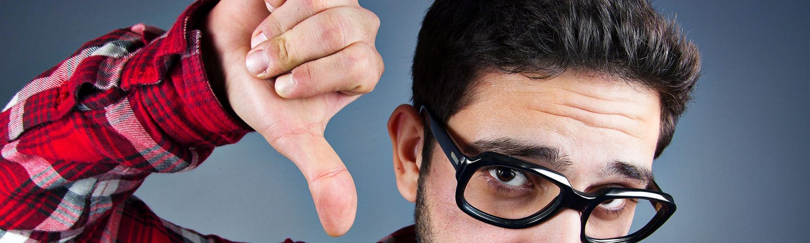 A man wearing glasses showing thumbs down