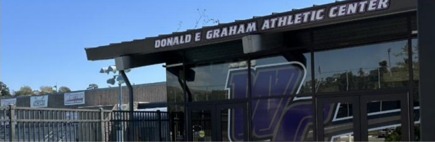 A portion of the Whittier College athletic center is in view. At the top of the building reads “Donald E. Graham Athletic Center,” but the last word is cut off by the photo. A large purple and gold “WC” is painted on the doors to represent Whittier College.