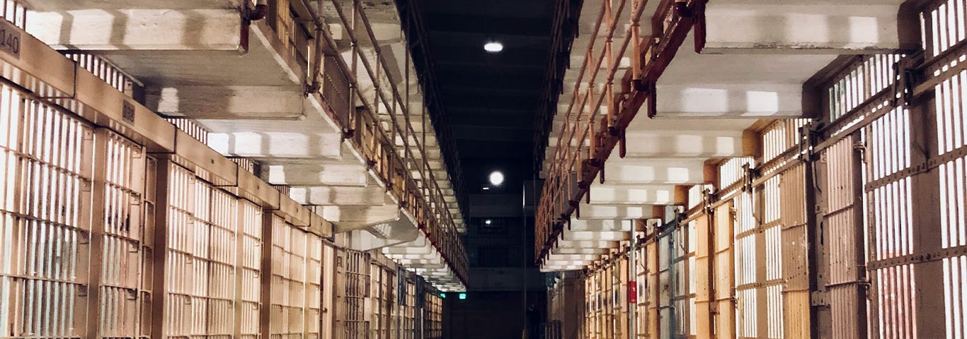 A long prison corridor with jail cells along each side