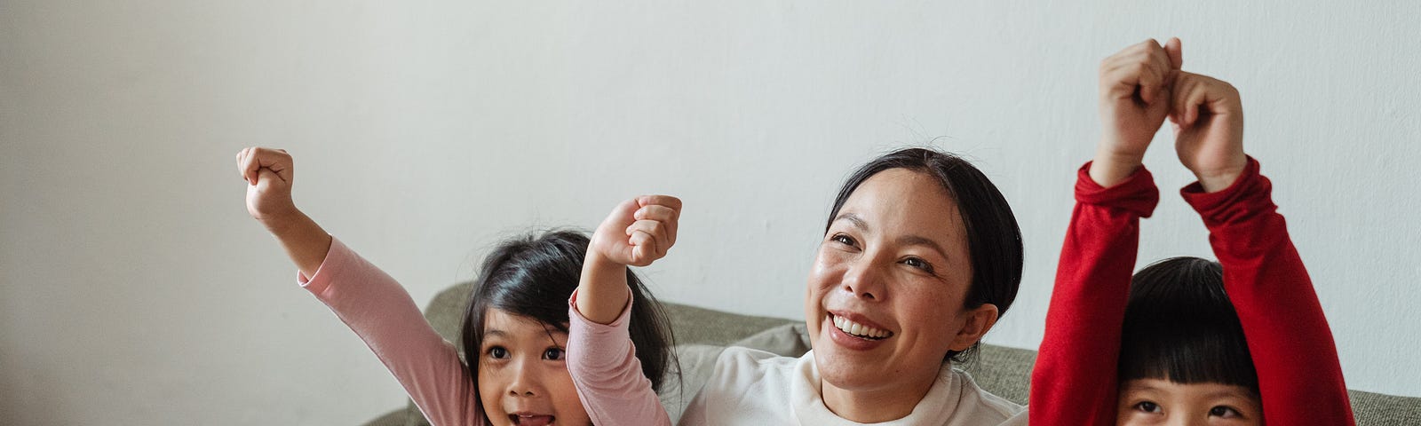 Happy Asian woman with kids cheering while watching TV