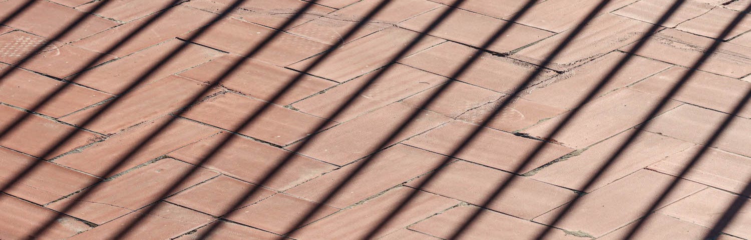 The shadow of metal railings on a red brick wall