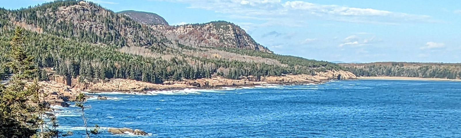 A view of rocky granite shoreline and hills.