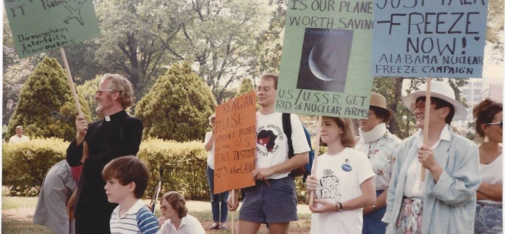 People standing in a park holding signs at an anti-nuclear weapons protest
