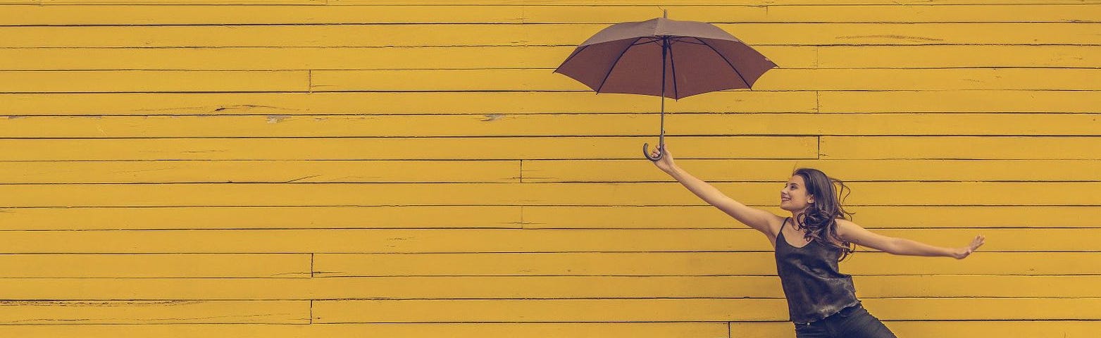 woman with umbrella in front of wall