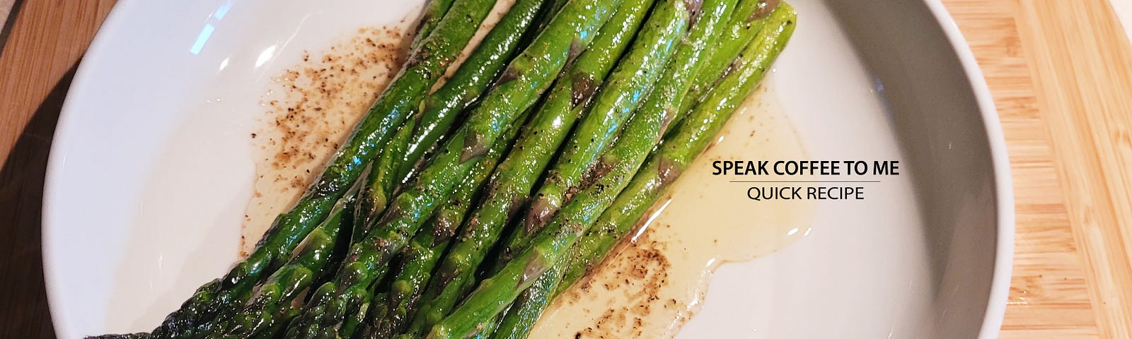 Cooked asparagus stalks in a shallow white bowl with melted butter