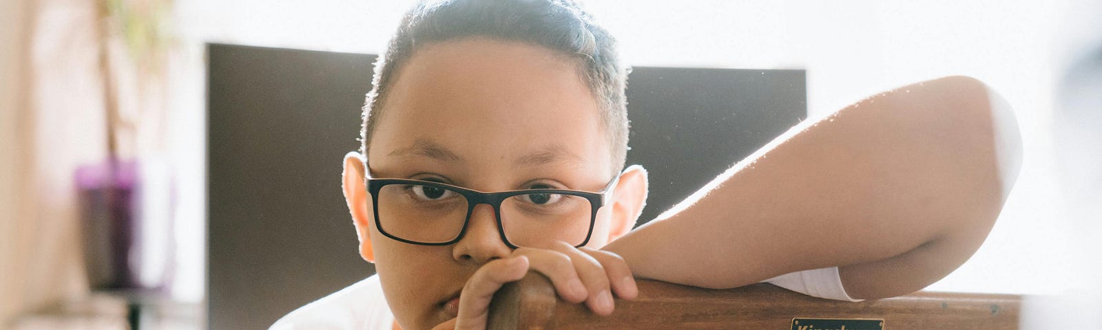 Little boy with glasses looking somber and staring straight into the camera