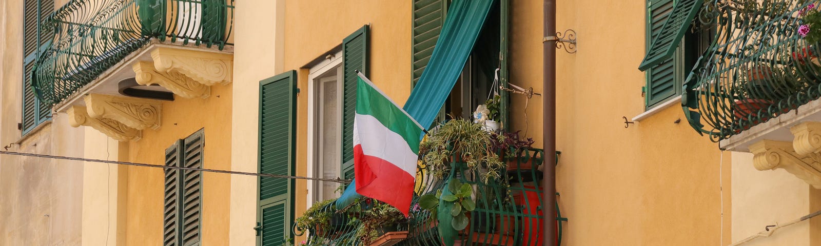 Closed balconies and windows; an Italian flag hanging