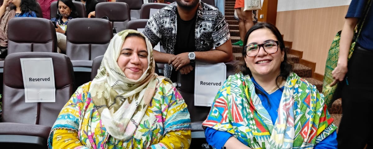 Zarghoona Wadood, Joshua Dilawer and Afsha Afridi, from PAN, smile at the camera together in the main auditorium at ARJC 2024.