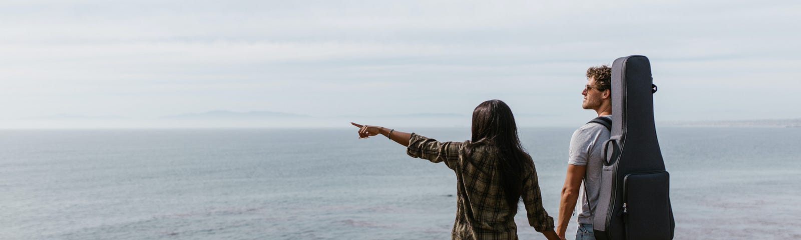 A couple holding hands, overlooking the ocean.