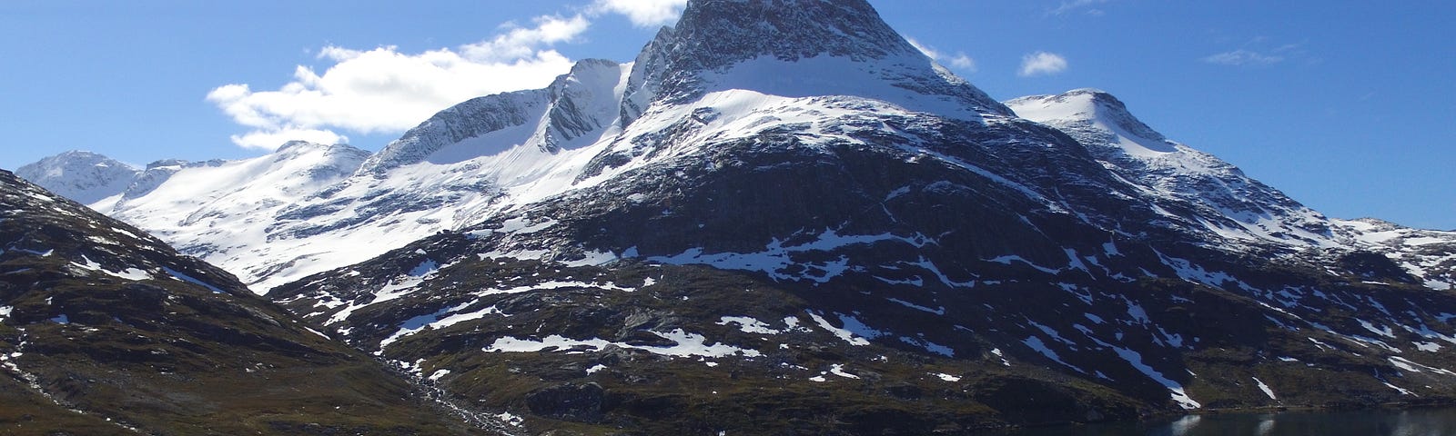 Drone photo of a sailboat anchored in the shadow of a snow-capped mountain in Greenland