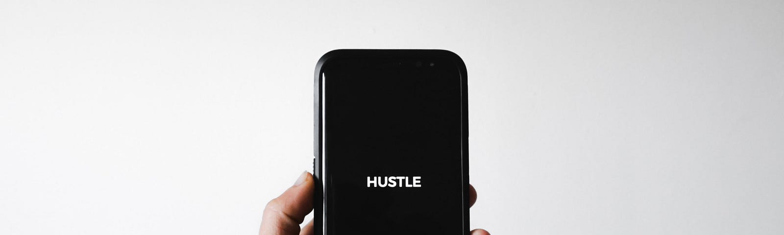 Smartphone displaying the word Hustle on a black screen.