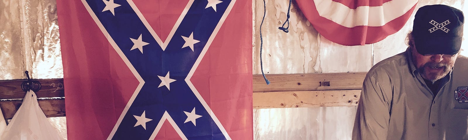 Inside the Sons of Conferacy  stall with a Confederate flag on the wall and a man standing behind a desk