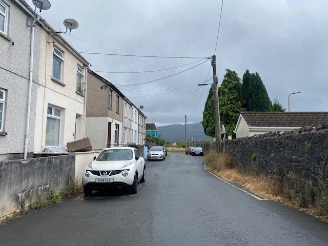 Looking down a residential street in Merthyr Tydfil in the foreground with hills in the background where there had been wildfires in 2022