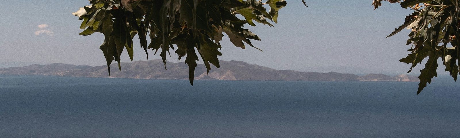 Two chairs and table facing blue sea and distant island